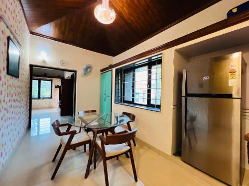 uma sala de jantar com uma mesa de vidro e um frigorífico em Anant Beach Villa em Ratnagiri