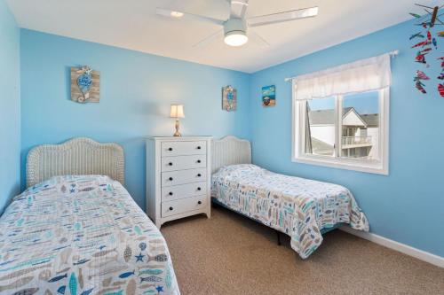 SC2C Sands Shamrock Oceanfront في كيل ديفيل هيلز: غرفة نوم زرقاء بسريرين ونافذة