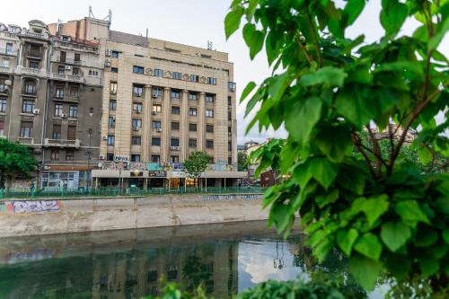 a building next to a river in front of a building at AIASTAY Bucharest River Apartments in Bucharest