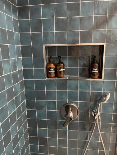 three bottles of alcohol on a blue tiled bathroom wall at Apartments INCIS next to the Pula Amphitheather in Pula