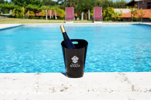 a wine bottle in a cup next to a swimming pool at Casa da Eira by Quantique in Amares