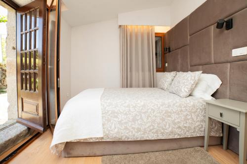 a bedroom with a white bed and a window at Casa da Eira by Quantique in Amares
