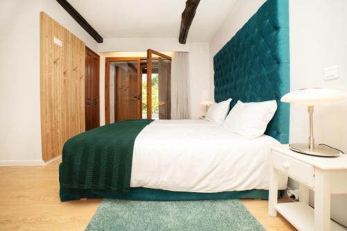 a bedroom with a large bed with a blue headboard at Casa da Eira by Quantique in Amares
