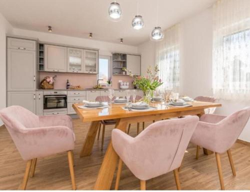een keuken met een houten tafel en roze stoelen bij VILLA ANITA in Sveti Filip i Jakov