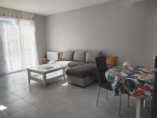 a living room with a couch and a table at Le palmier nantais in Mouzeil