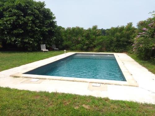 a swimming pool in a yard with a grass field at Maison des Soupirs in Montpon-Ménestérol