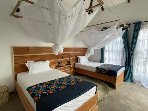 - 2 lits dans une chambre avec moustiquaires dans l'établissement Tanzania Safari Lodge, à Arusha