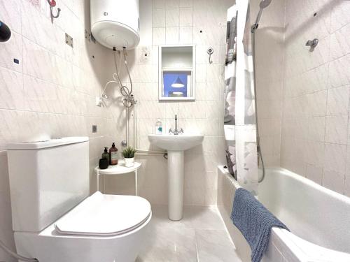 a bathroom with a toilet and a sink and a tub at White studio in Torrevieja