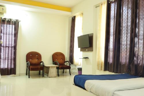 um quarto com duas camas e duas cadeiras e uma televisão em Hotel Kanchan Palace em Indore