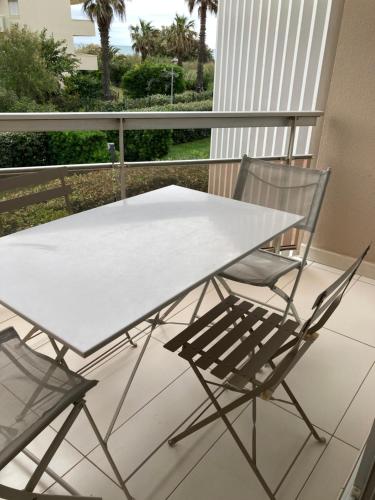 d'une table blanche et de deux chaises sur un balcon. dans l'établissement SAIT CYPRIEN VUE MER résidence avec piscine, à Saint-Cyprien