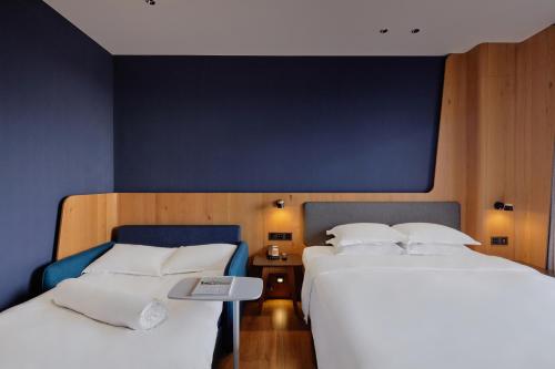 two beds in a room with a blue wall at Holiday Inn Express Chiayi by IHG in Chiayi City