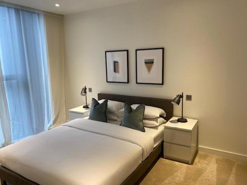 ロンドンにあるCanary Wharfのベッドルーム(白い大型ベッド、ランプ2つ付)