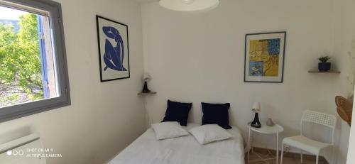 une chambre blanche avec un lit et une fenêtre dans l'établissement La petite maison, mer et colline, à Carqueiranne