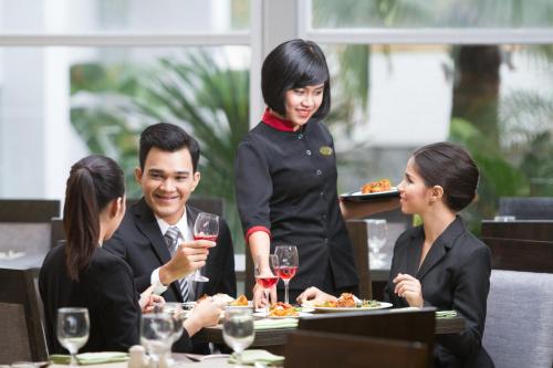 a waitress serving a group of people in a restaurant at Santika Premiere Dyandra Hotel & Convention - Medan in Medan