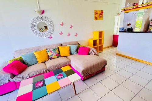 a living room with a couch with colorful pillows at La vie en rose: piscine et vue mer in Le Gosier