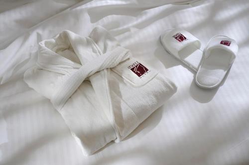 a white towel and a pair of shoes on a bed at Semeli Hotel in Nicosia
