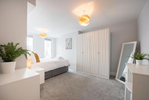 a white bedroom with a bed and a cabinet at Modern,Bright and spacious 2 bed in Brentwood