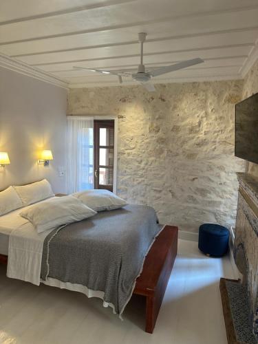 a bedroom with a bed and a stone wall at Castellorizon Pensione in Meyisti