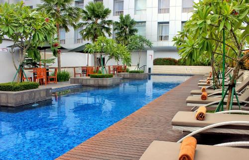 a hotel swimming pool with palm trees and a building at Santika Premiere Dyandra Hotel & Convention - Medan in Medan