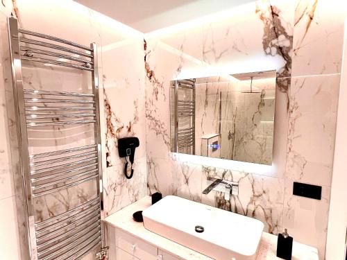 uma casa de banho branca com um lavatório e um espelho em ILLYRIAN hotel em Ksamil