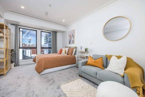 オークランドにあるCBD Studio Getawayのベッドルーム(ベッド1台、ソファ、鏡付)