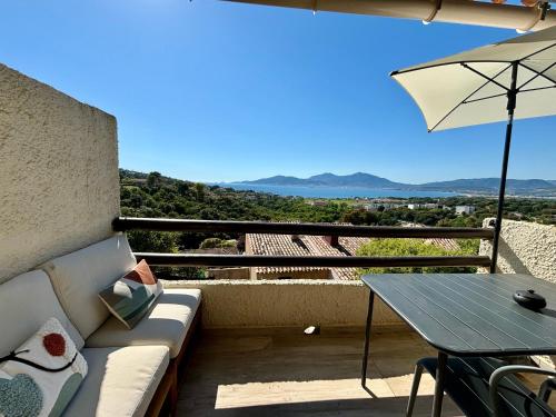 eine Terrasse mit einem Sofa, einem Tisch und einem Sonnenschirm in der Unterkunft Studio Vue Mer - Piscine - Porticcio in Porticcio