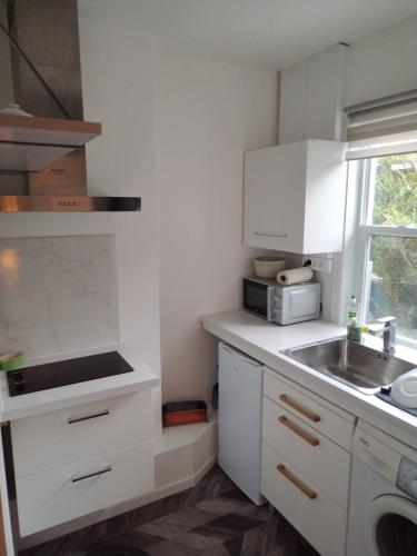 uma cozinha branca com um lavatório e um micro-ondas em Appartement indépendant Ô Bohème em Fourqueux
