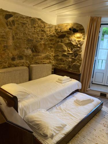 a bedroom with a bed and a stone wall at Casa Flor de Lis, Sardoal in Sardoal