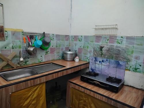una cocina con encimera y ordenador portátil. en Atta Ratu Homestay, en Komodo