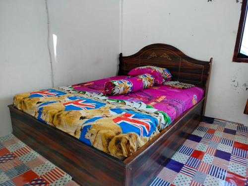 ein Bett mit einer bunten Bettdecke und Kissen darauf in der Unterkunft Atta Ratu Homestay in Komodo