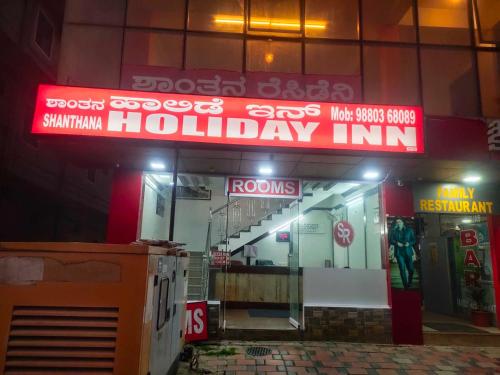 un edificio con un cartel que lee Holiday inn en Shanthana holiday inn coorg en Kushālnagar