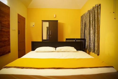a yellow bedroom with a bed with two pillows at New Heaven Group accommodation in Thekkady