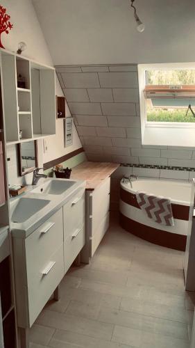 une petite cuisine avec un évier et une baignoire dans l'établissement Maison La Suze, à La Suze-sur-Sarthe