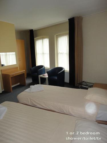a hotel room with two beds and chairs and windows at Hotel 't Anker in Leeuwarden