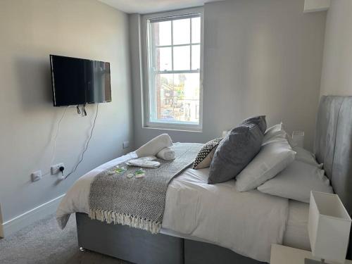 een slaapkamer met een bed met kussens en een flatscreen-tv bij Bright, spacious 1 bedroom flat in Brentwood