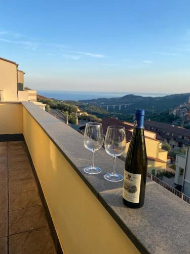 a bottle of wine and two wine glasses on a ledge at Liguria sole mare e relax in Civezza