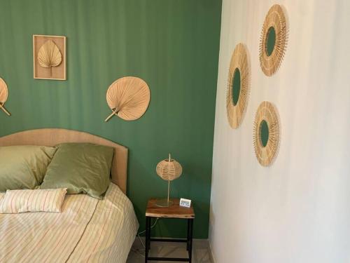Un dormitorio con paredes verdes con una cama y una mesa. en Rez de maison neuve Piscine WiFi Poolhouse en Pierre, en Penta-di-Casinca