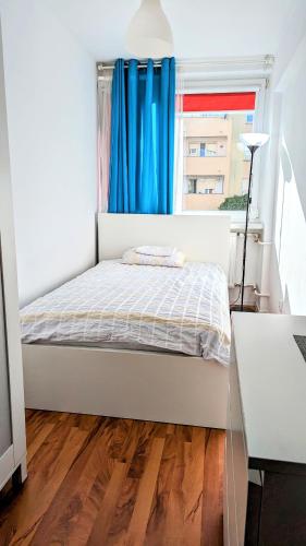 1 dormitorio con 1 cama y una ventana con cortinas azules en Ursus Rooms-Self Check-in en Varsovia