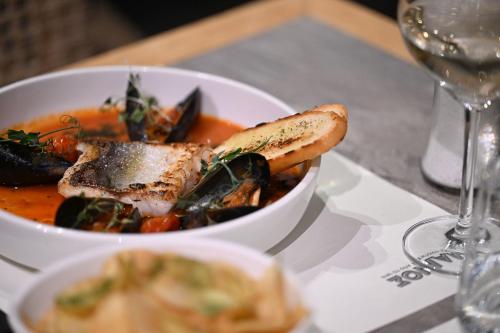 a bowl of food on a table with a wine glass at Skiathos Thalassa Cape Hotel, Philian Hotels and Resorts in Megali Ammos
