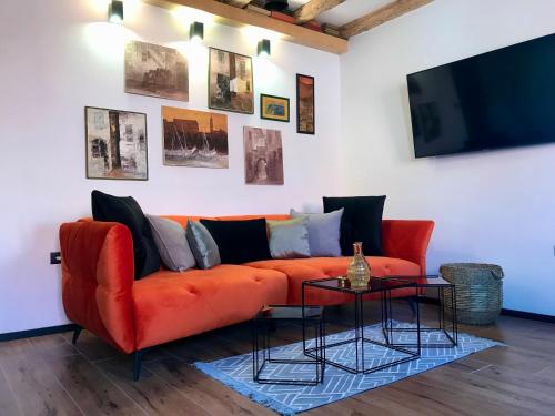 ein Wohnzimmer mit einem orangenen Sofa und einem TV in der Unterkunft Split Centar Diocletian's Palace in Split