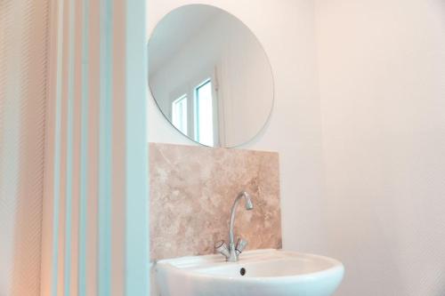 a bathroom with a white sink and a mirror at L'Etape - La Maison des amis in Tours