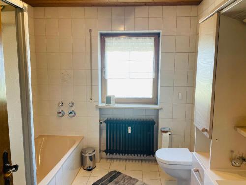 een badkamer met een bad, een toilet en een raam bij Ferienwohnung Alpenblick in Bruckmühl