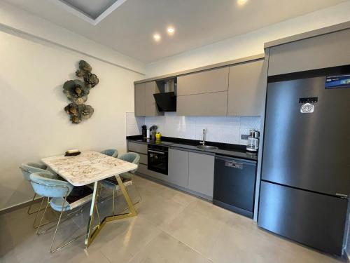 a kitchen with a table and a stainless steel refrigerator at SA Apartments! 1bd Flat 300m to the Beach in Alanya