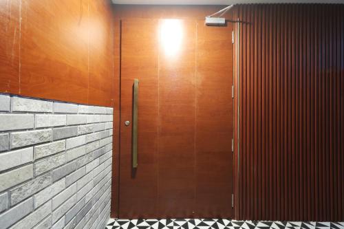 a wooden door in a bathroom with a brick wall at Hotel Aura Dombivali in Dive