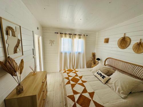 a bedroom with a bed and a wooden table at Cabane le Flamant avec jardin, piscine chauffée et parking in Saintes-Maries-de-la-Mer