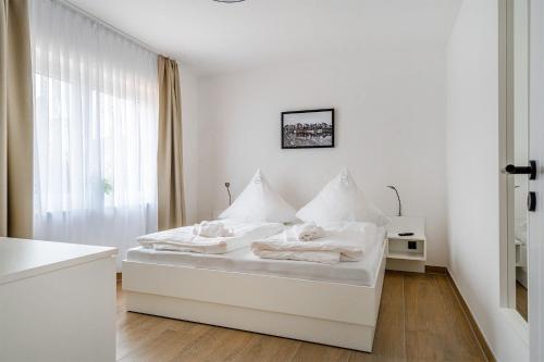 um quarto branco com uma cama com lençóis brancos e uma janela em In't Dörp 1, super zentral mit eigenem Garten und Parkplatz! em Greetsiel