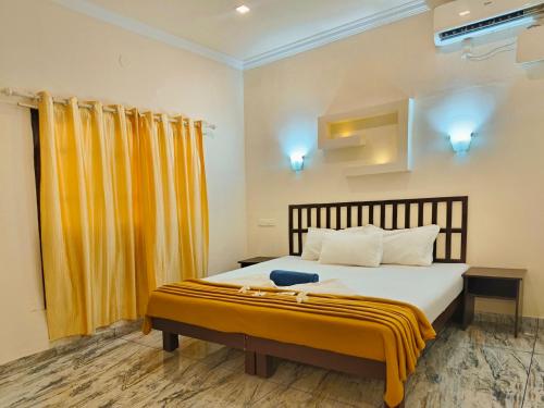 a bedroom with a large bed with yellow curtains at Marari Blue Waves in Mararikulam