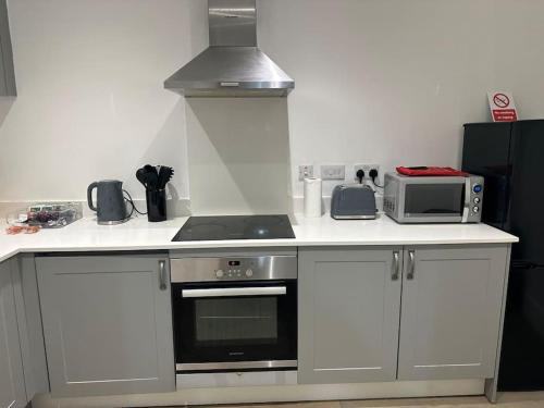 una cocina con estufa y microondas en Bright, spacious and modern flat, en Brentwood