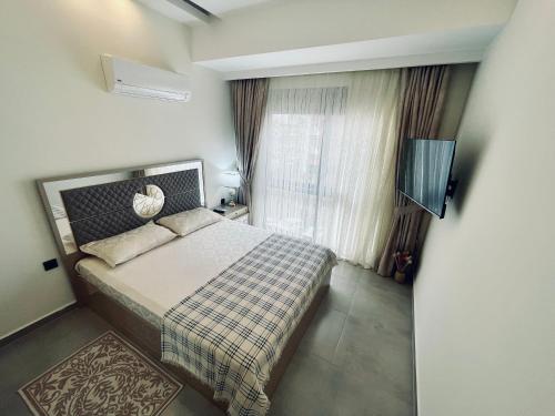 a bedroom with a bed and a window and a television at SA Apartments! 1bd Flat 300m to the Beach in Alanya