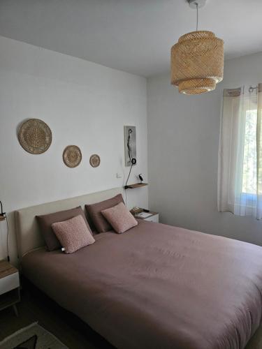 une chambre avec un grand lit avec des oreillers roses dans l'établissement Les Lambrusques T2 avec jardin à 300 m de la plage, à Cavalaire-sur-Mer